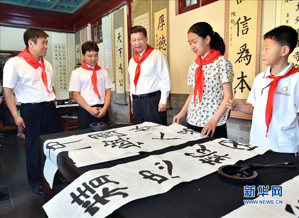 习近平观看学生书写的毛笔字。