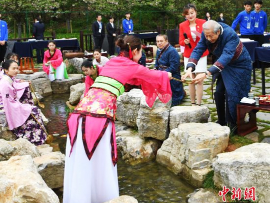 来自海内外的书法家身着晋服，在曲水边品酒、赋诗、挥毫。